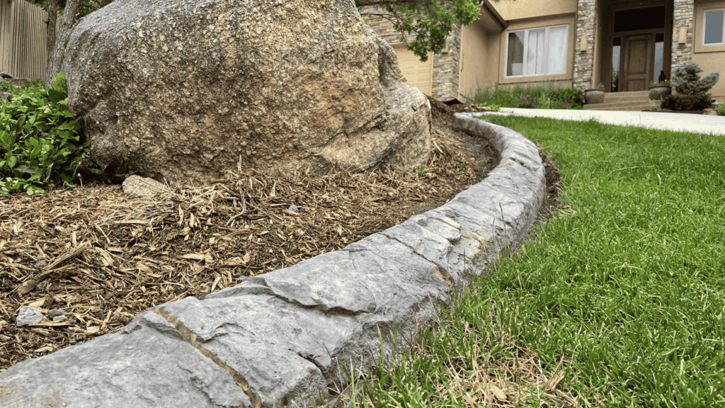 Concrete edging separating decorative bark mulch from grass.